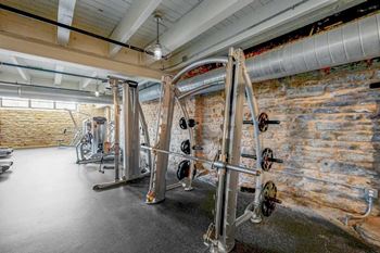 A gym with a brick wall and a row of exercise machines.